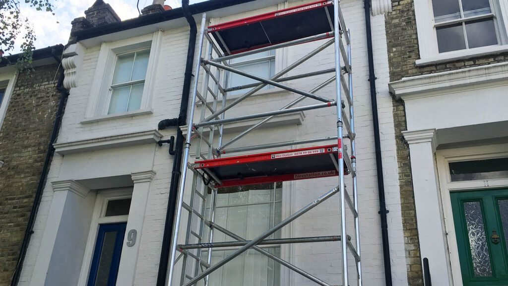 Front View Of A House With A Tower Scaffold Set Up, Prepared For Exterior Painting And Renovation Work.